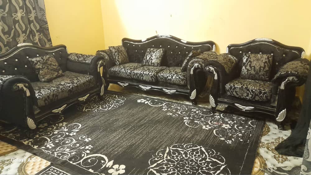 Salon complet d\'occasion en bon état avec tapis et rideaux.