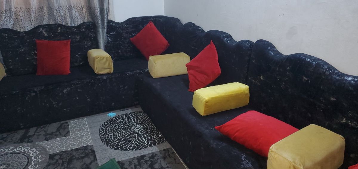 Salon saoudien neuf avec coussins rouges et tapis décoratif